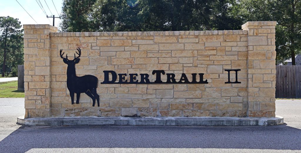 The Deer Trail II entrance sign, with a black deer silhouette on a limestone wall