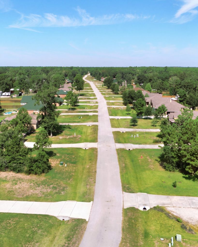 Aerial view down a long, straight Deer Trail II street lined with homes and lawns